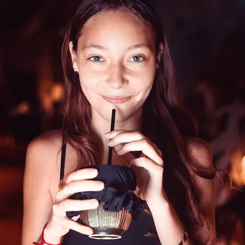 Chica bebiendo con pajita de un vaso cubierto con Tailsip negro